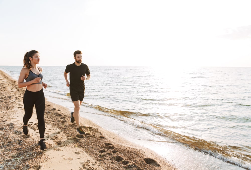 homme et femme qui pratiquent la course à pied sur une plage propre